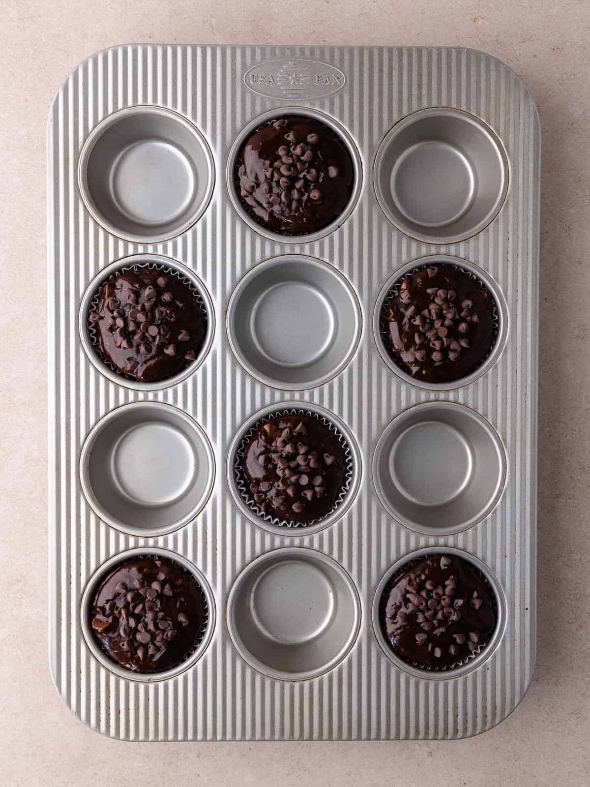 Chocolate muffin batter is filled in every other well.