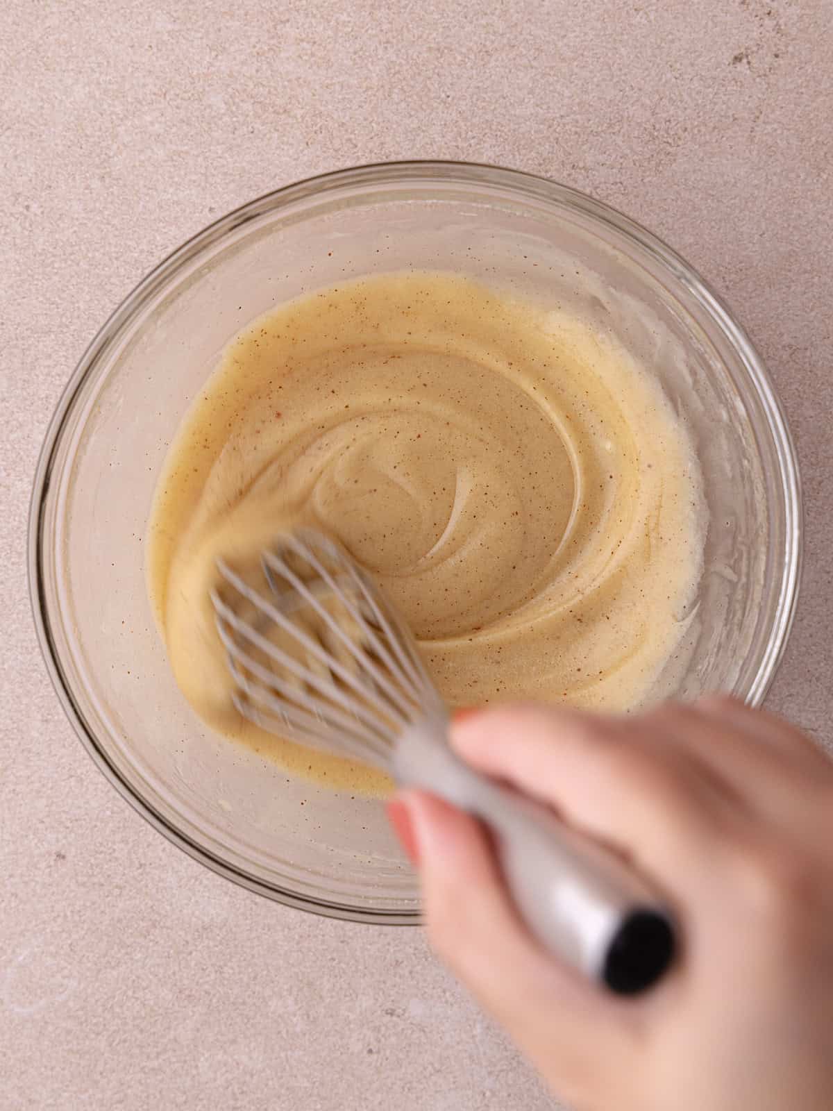 Brown butter apple cider glaze is whisked in a small bowl.