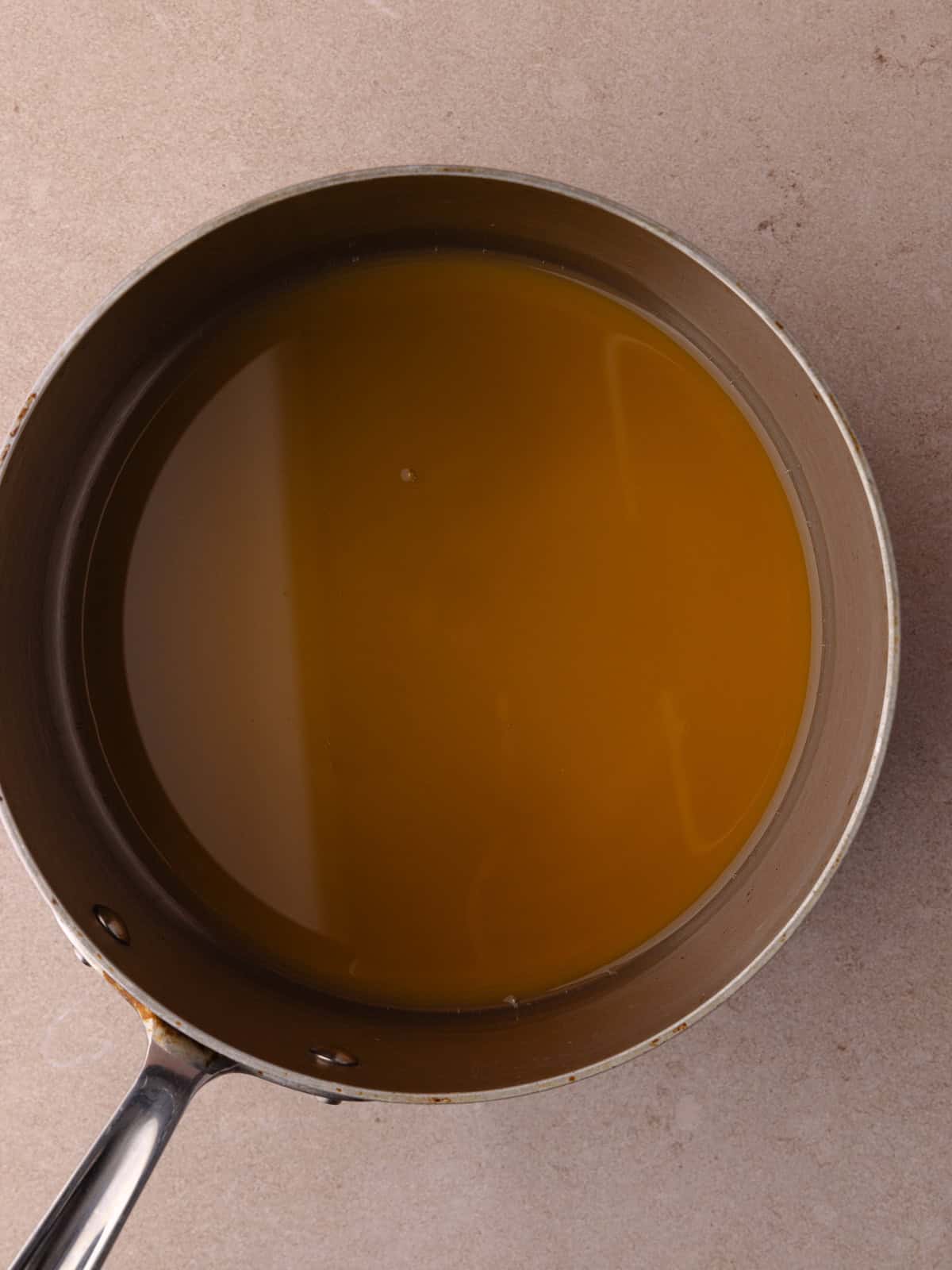 Apple cider is added to a saucepan.