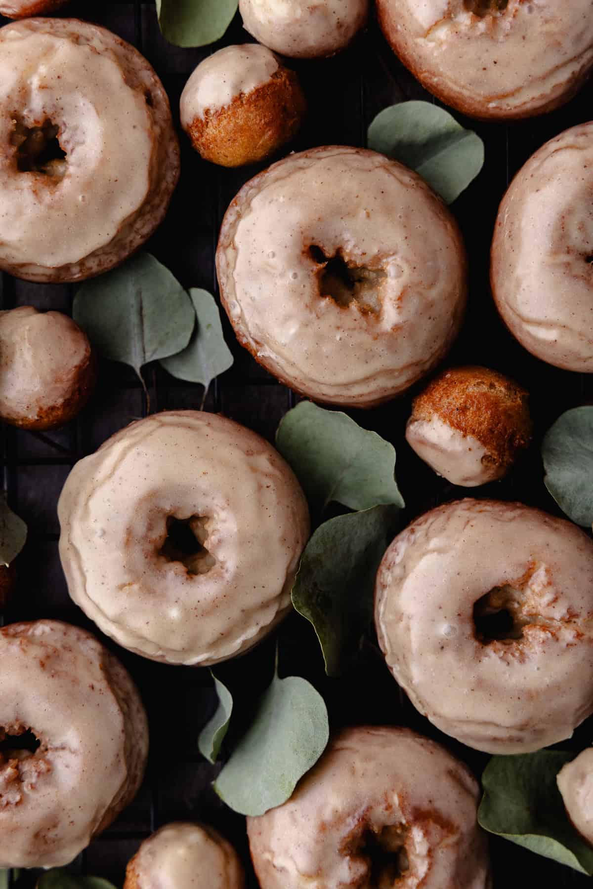 Glazed apple cider donuts and donut holes are on a wire rack.