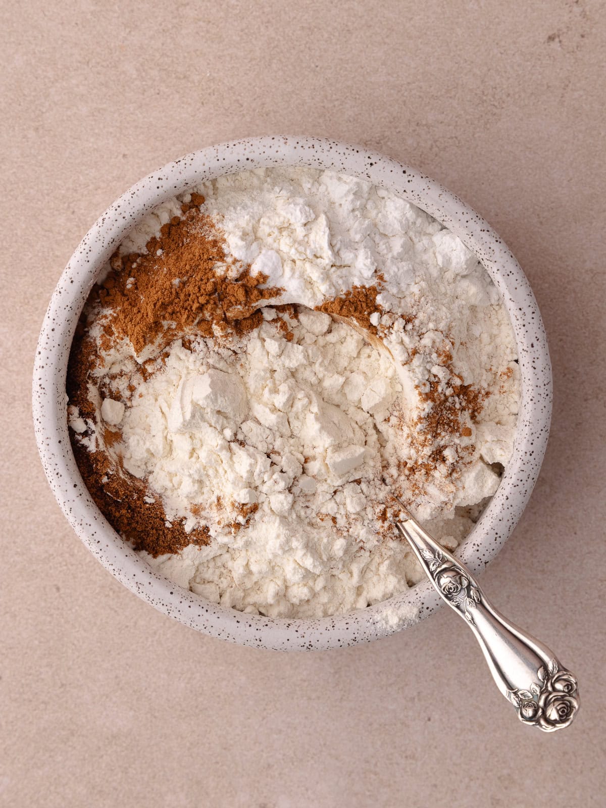 All purpose flour, baking powder, baking soda, cinnamon, cloves, nutmeg and salt are combined in a bowl.