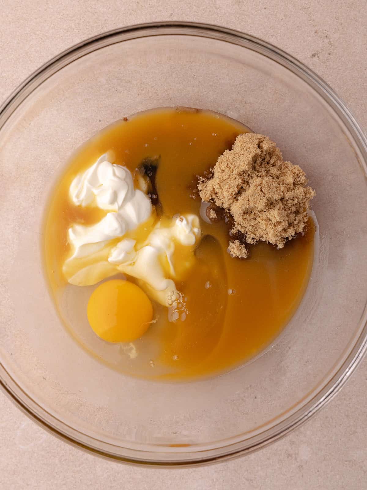 Brown sugar, sour cream, reduced apple cider, melted butter, an egg and vanilla paste are in a medium bowl.