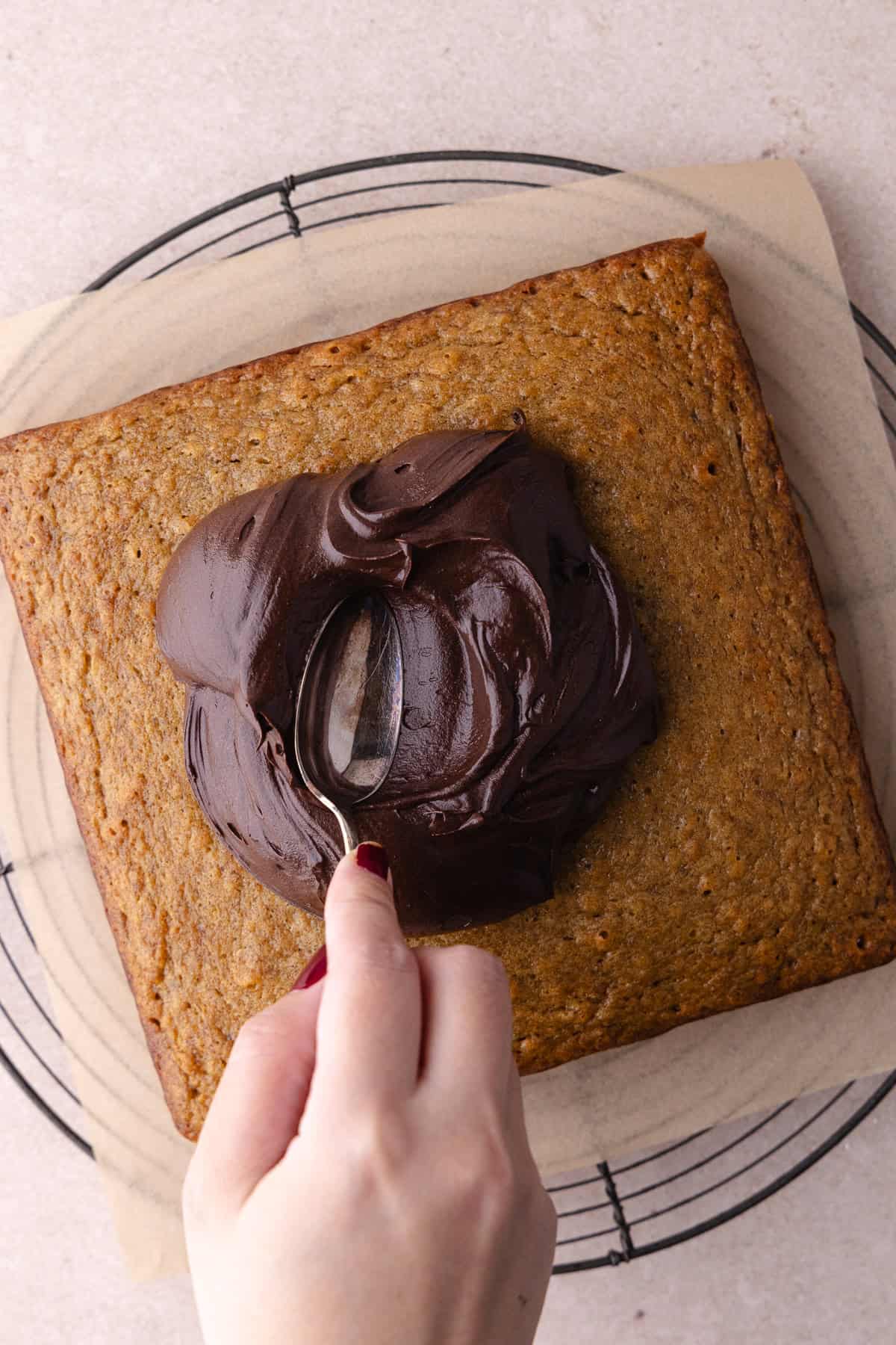 Cake gets frosted with chocolate frosting.