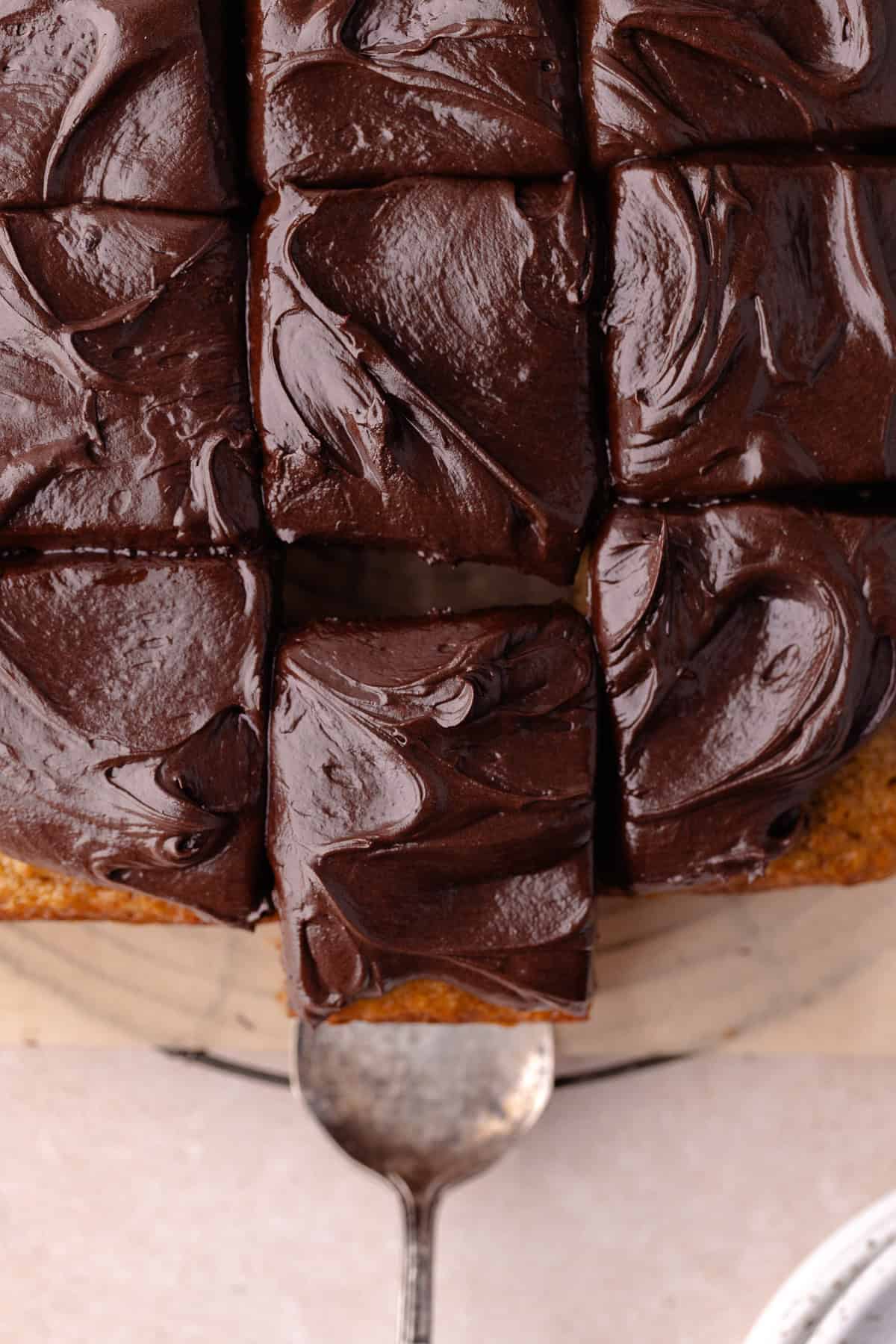 A cake serve pulls out a slice of banana cake with chocolate frosting.