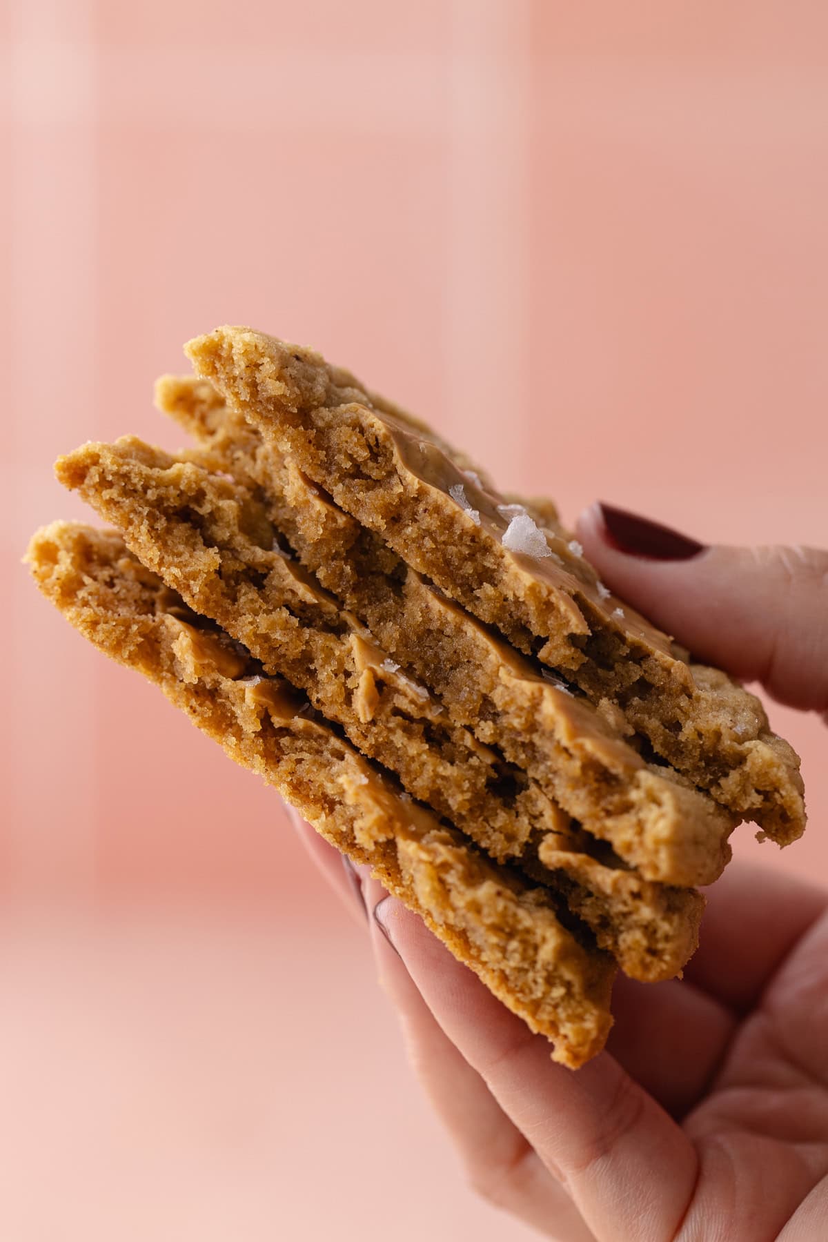 A hand holds a stack of cookies exposing the inside.