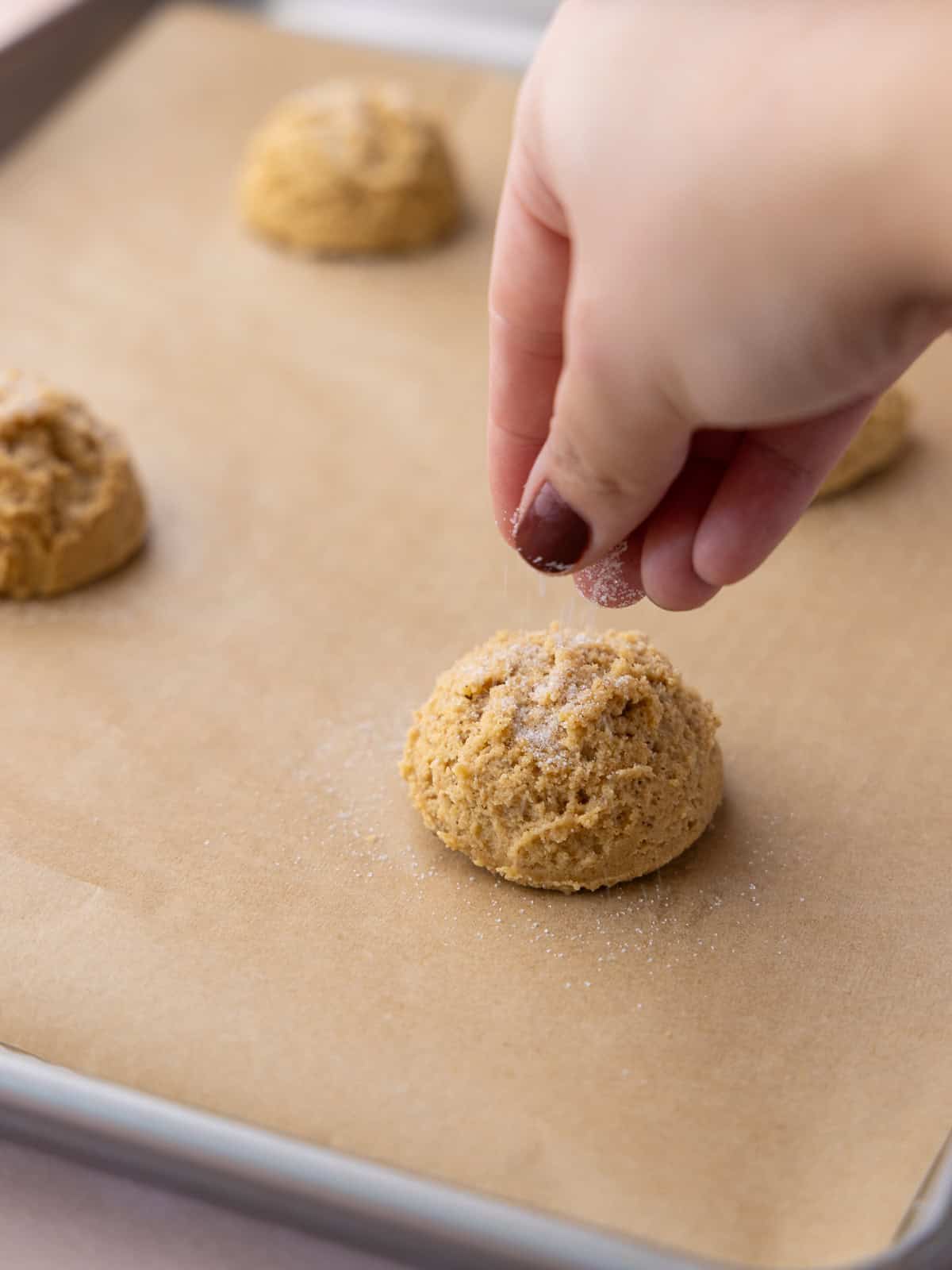 White sugar is sprinkled on top of the scoops of cookie dough.