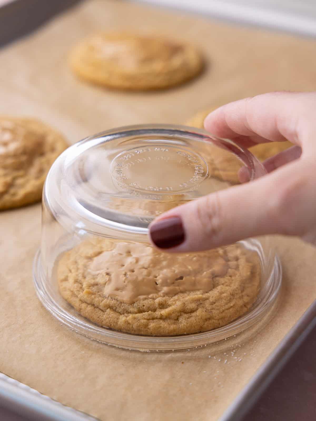 A glass bowl is place over a cookie to round out the cookies egdes.