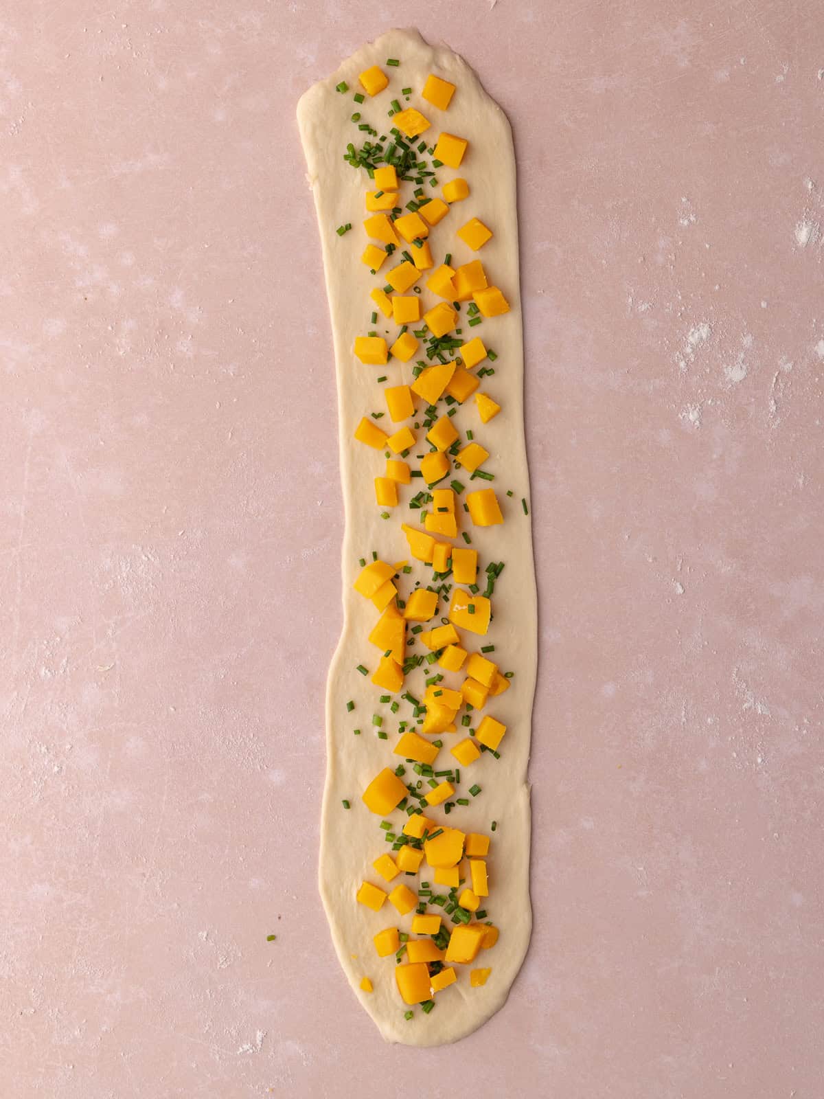 Chives and cheddar cheese cubes are added to the middle of the dough.