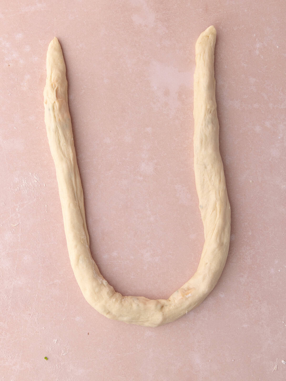 A long rope of dough is shaped in a U shape.