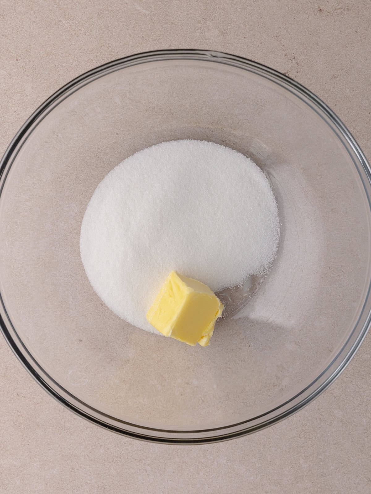 White sugar and softened butter are in a large glass bowl.