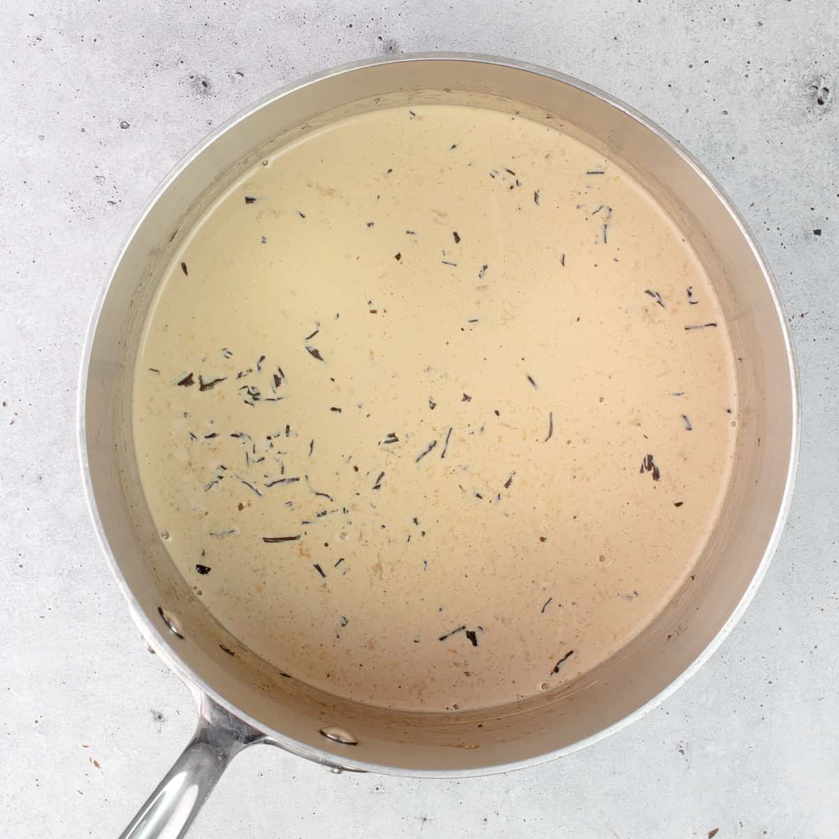 Earl grey tea leaves are steeping in a saucepan with hot cream.