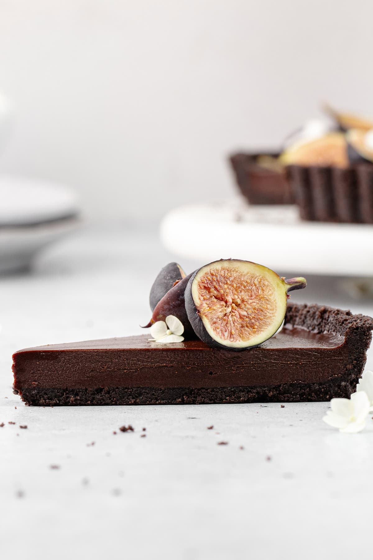 A close up of the side view of a slice of chocolate earl grey tart garnished with fresh figs.