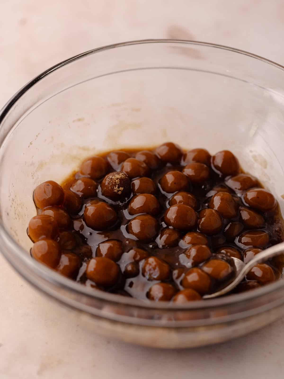 Boba pearls are in a bowl and stirred with brown sugar.