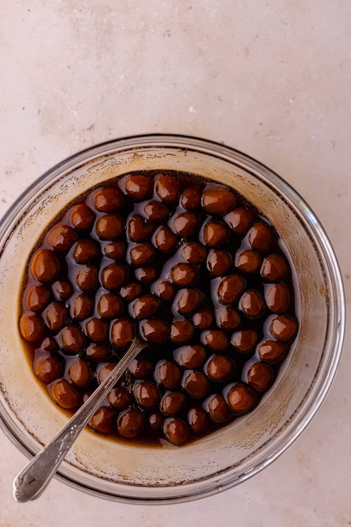 Boba pearls in a bowl of sugar syrup.