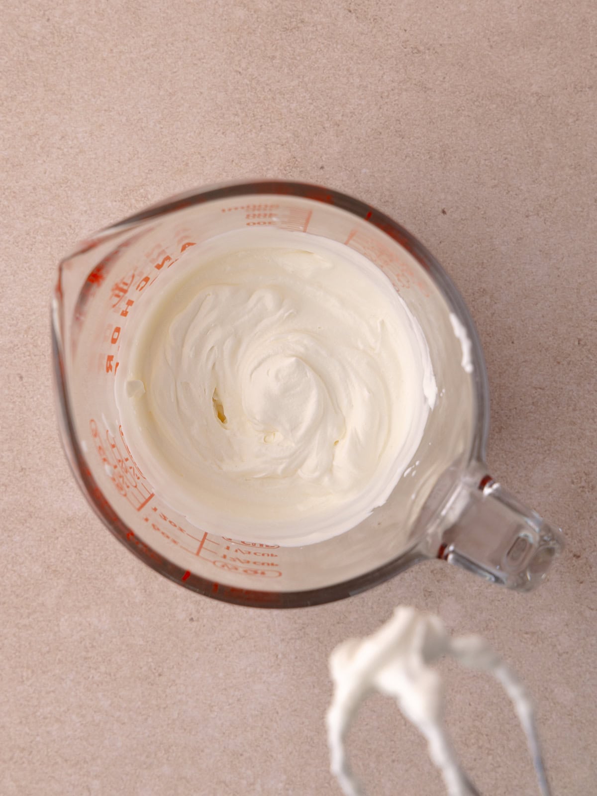 Heavy cream is whipped in a measuring cup, with a single beater of a hand-held mixer until it reaches stiff peaks.