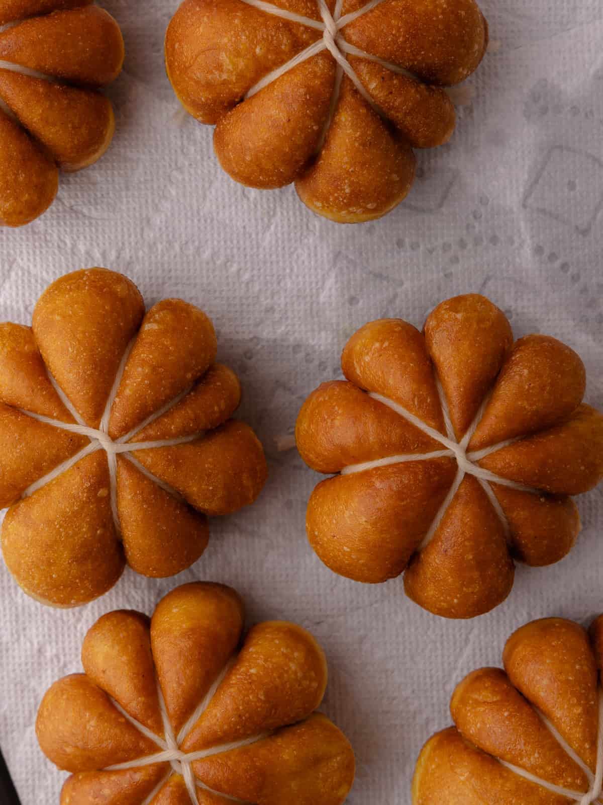 Donuts are fried until golden brown and are placed on a wire rack lined with paper towels.