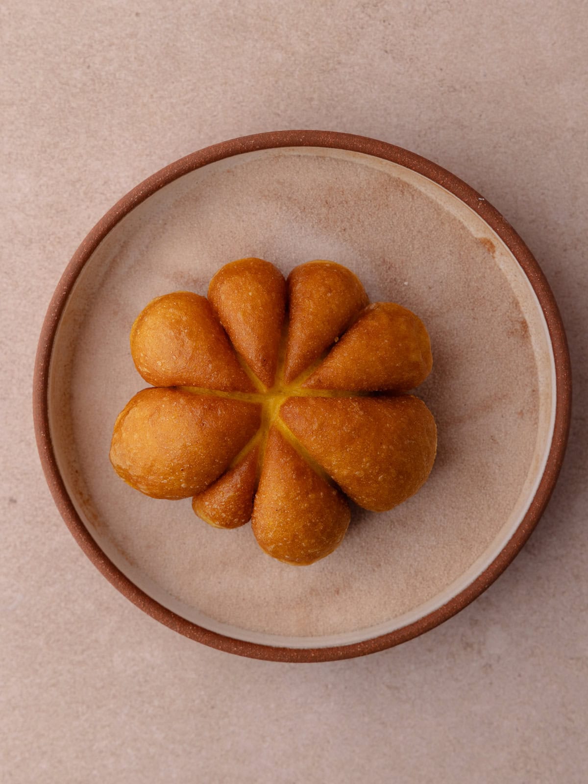 Fried pumpkin donuts are coated in cinnamon sugar is a shallow bowl.