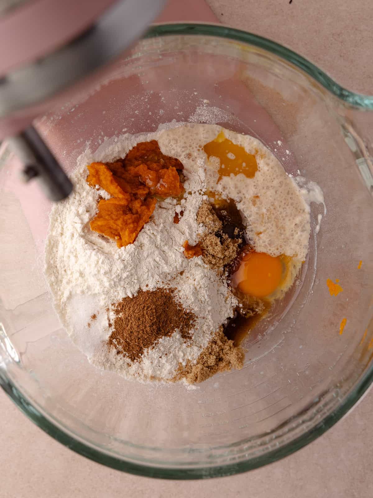 The bread flour, all purpose flour, the remaining brown sugar, egg, melted butter, salt pumpkin puree, and pumpkin pie spice is added to the bowl of the stand mixer with the bloomed yeast.