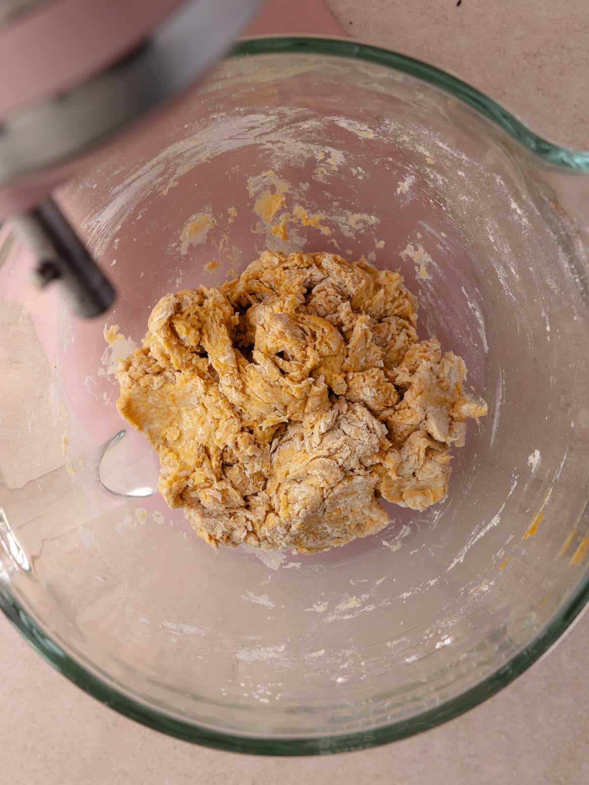 The pumpkin dough mixture is mixed together until a shaggy ball of dough forms.