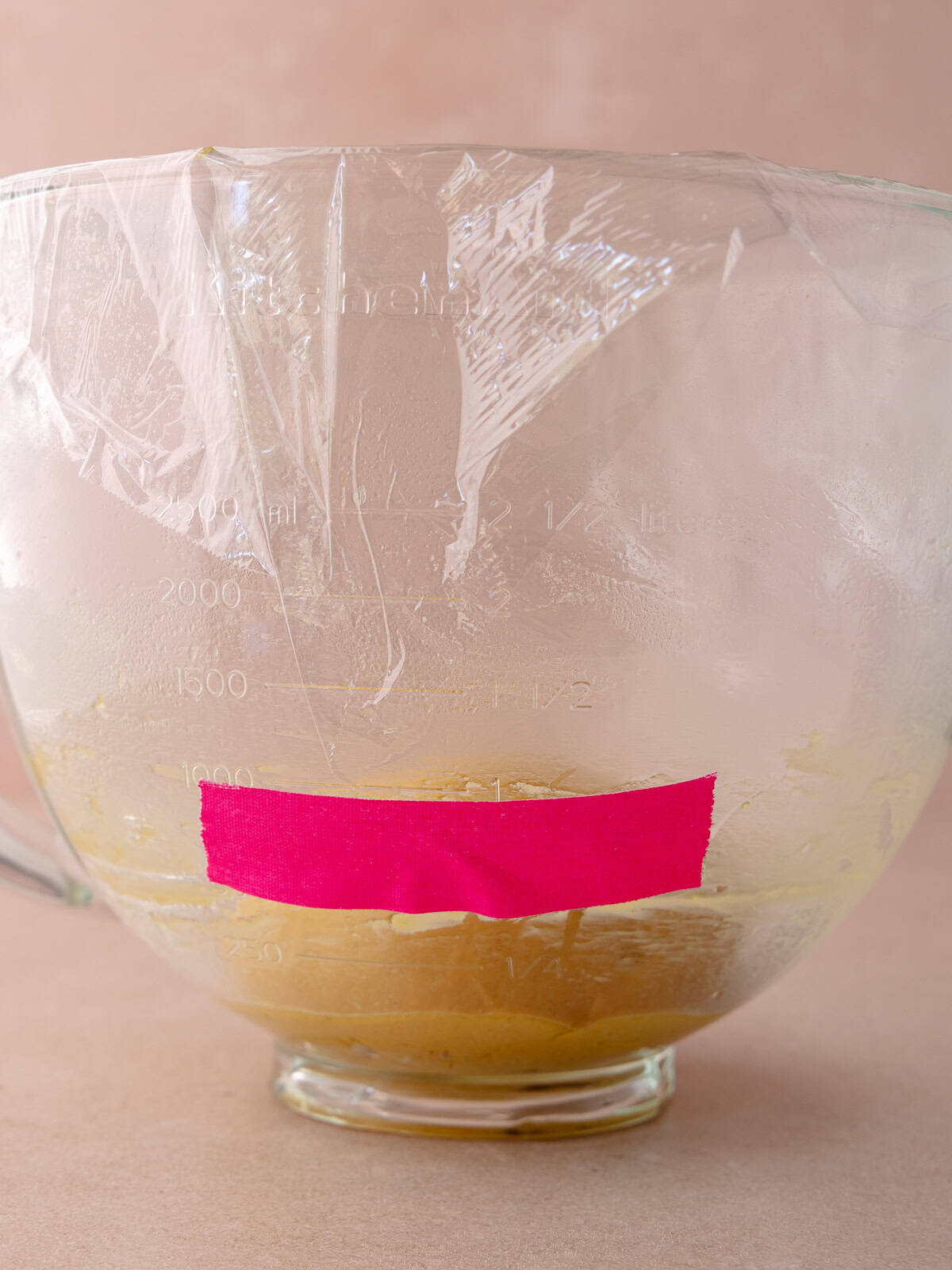 The pumpkin donut dough is ready for the first rise. A piece of tape is tapped to the side of the stand mixer bowl to monitor the growth of the dough.