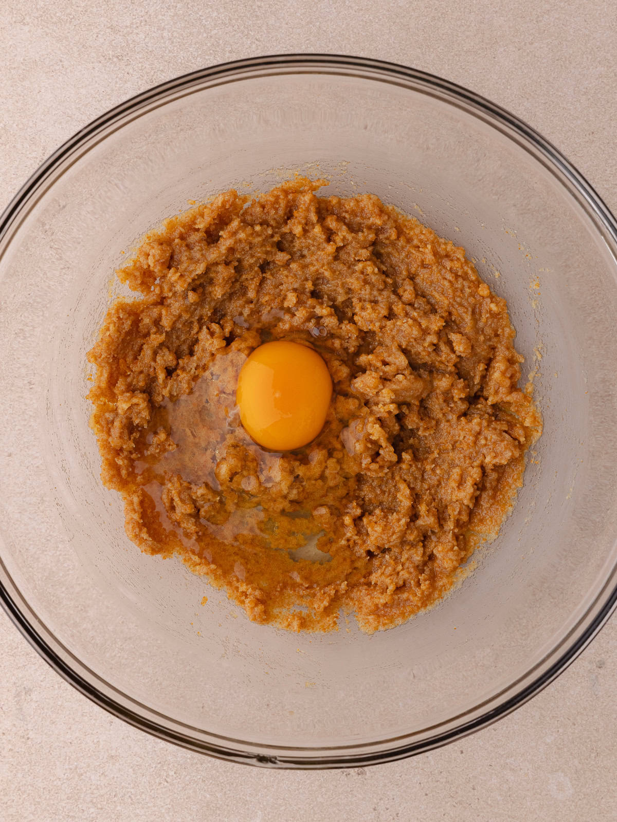 An egg is cracked into the bowl with the brown butter, toasted milk powder and sugar mixture.