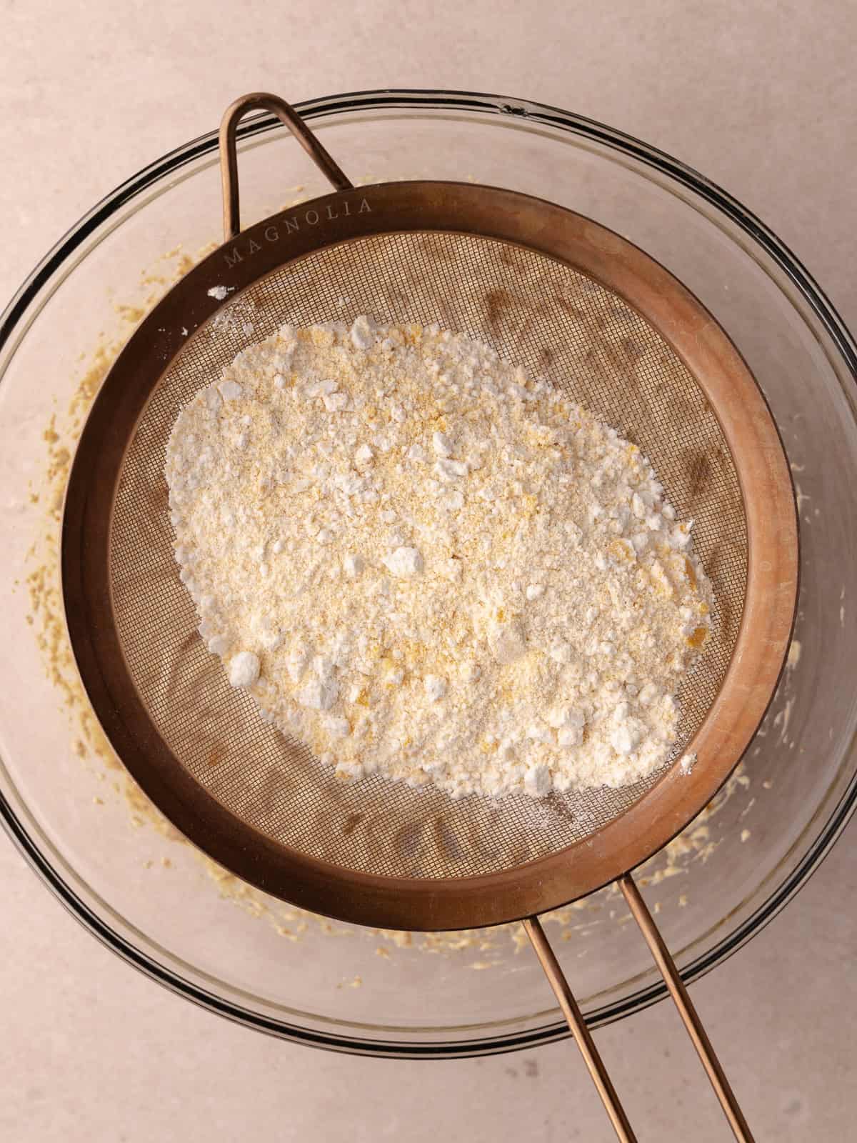 Dry ingredients are sifted into the bowl of butter sugar and egg mixture.