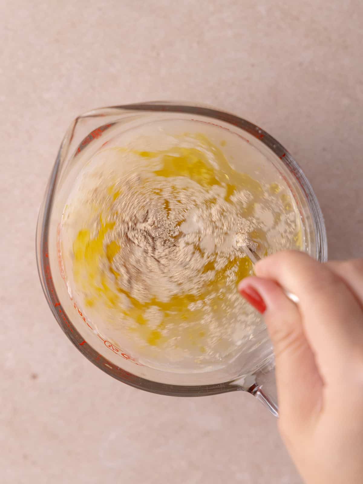 Warm water, yeast, sugar and olive oil are mixed together in a large measuring cup.