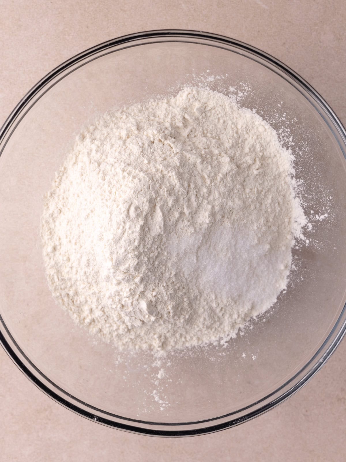 Bread flour and salt are sitting in a large glass bowl.