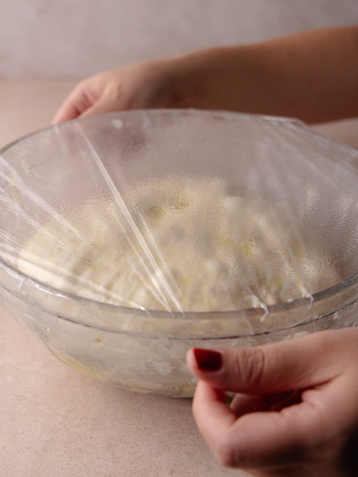 Plastic wrap is placed over the bowl of dough.