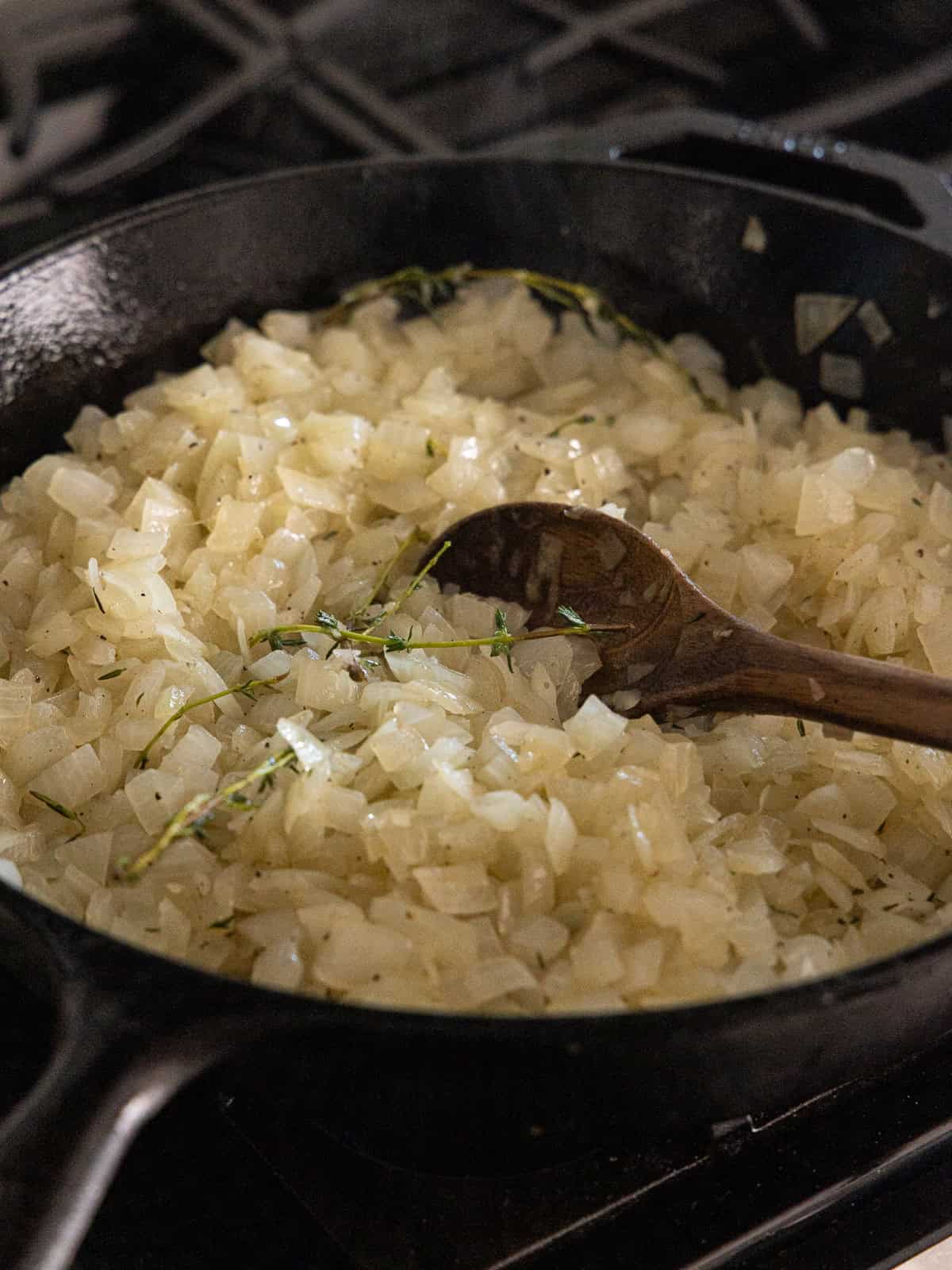 Diced onions, thyme, salt and pepper are cooked in a large cast iron pan.