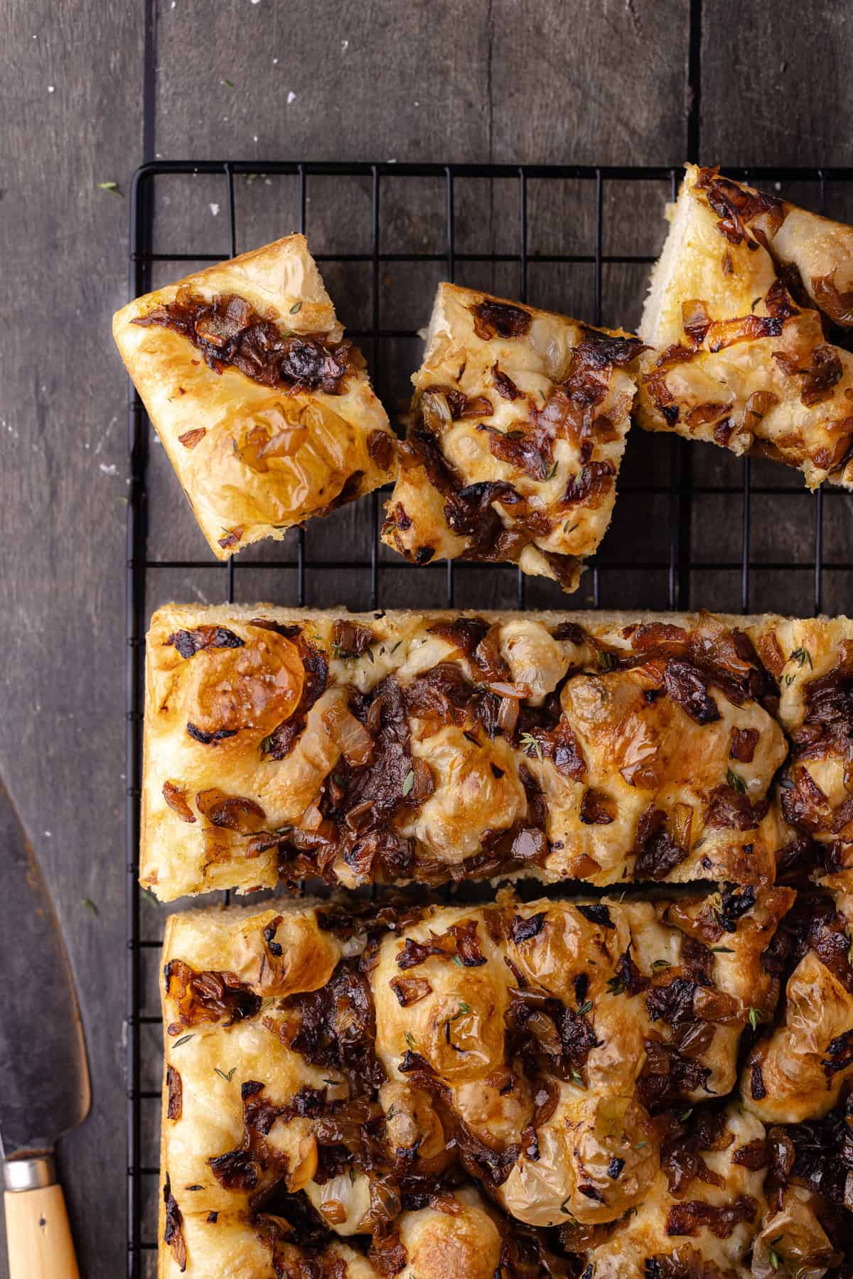 Overnight caramelized onion focaccia cut into small squares and sitting on a wire rack.