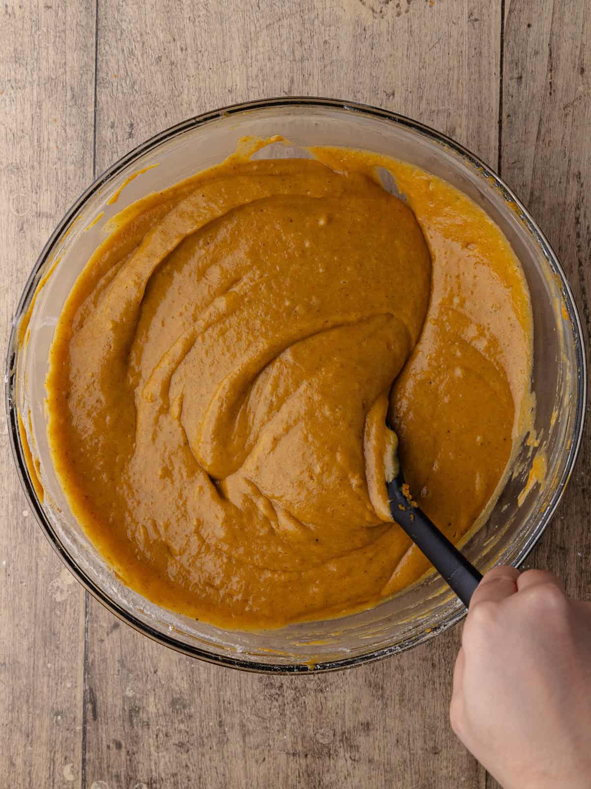 Chai pumpkin cake batter is mix together in a large glass bowl.