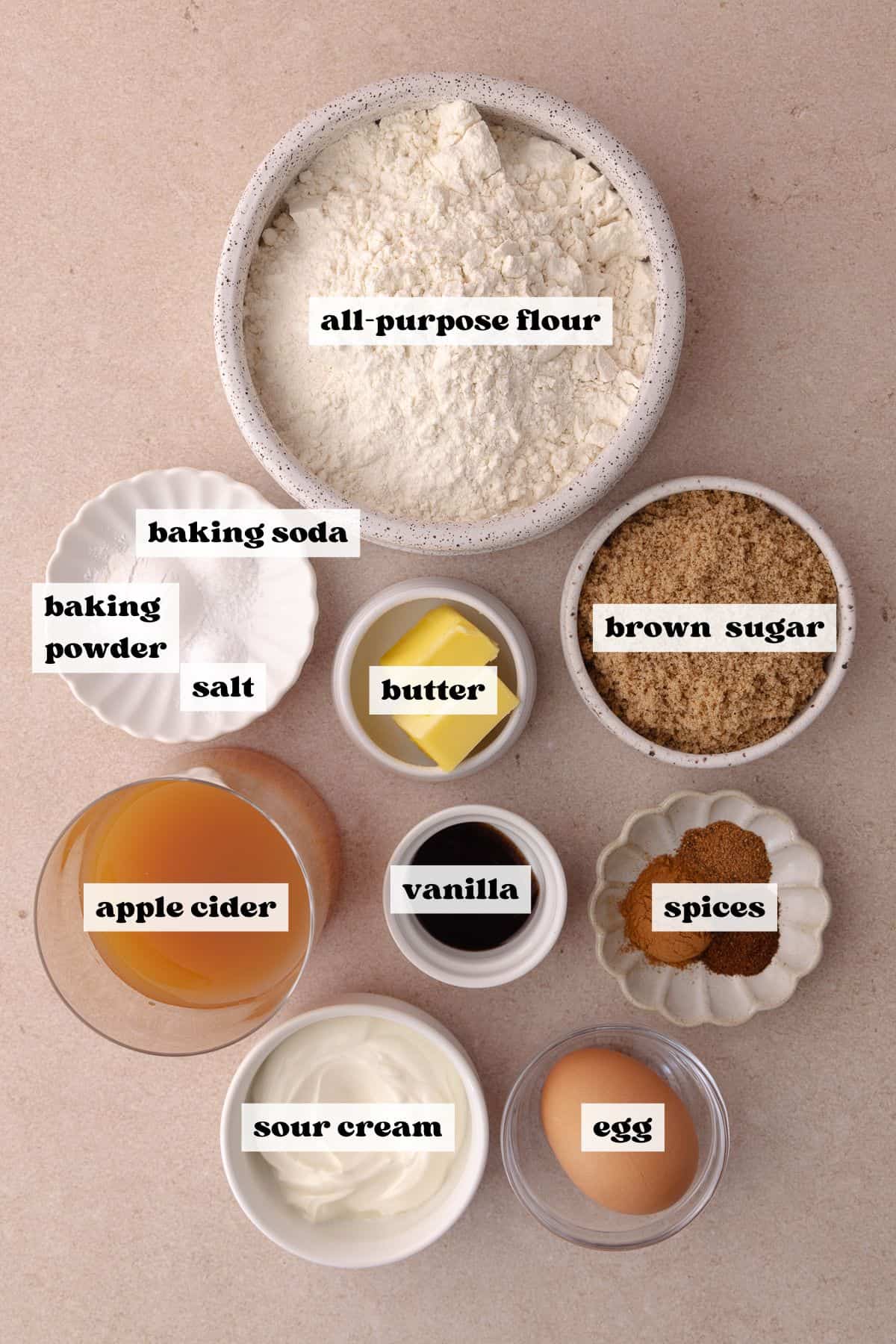 Small batch apple cider donut dough ingredients which include, all-purpose flour, baking soda, baking powder, salt, cinnamon, clove, nutmeg, brown sugar, sour cream, butter, an egg, apple cider and vanilla paste.