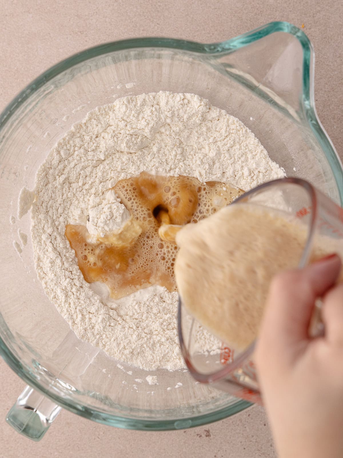 Frothy yeast mixture is added to the bowl with bread flour and salt.