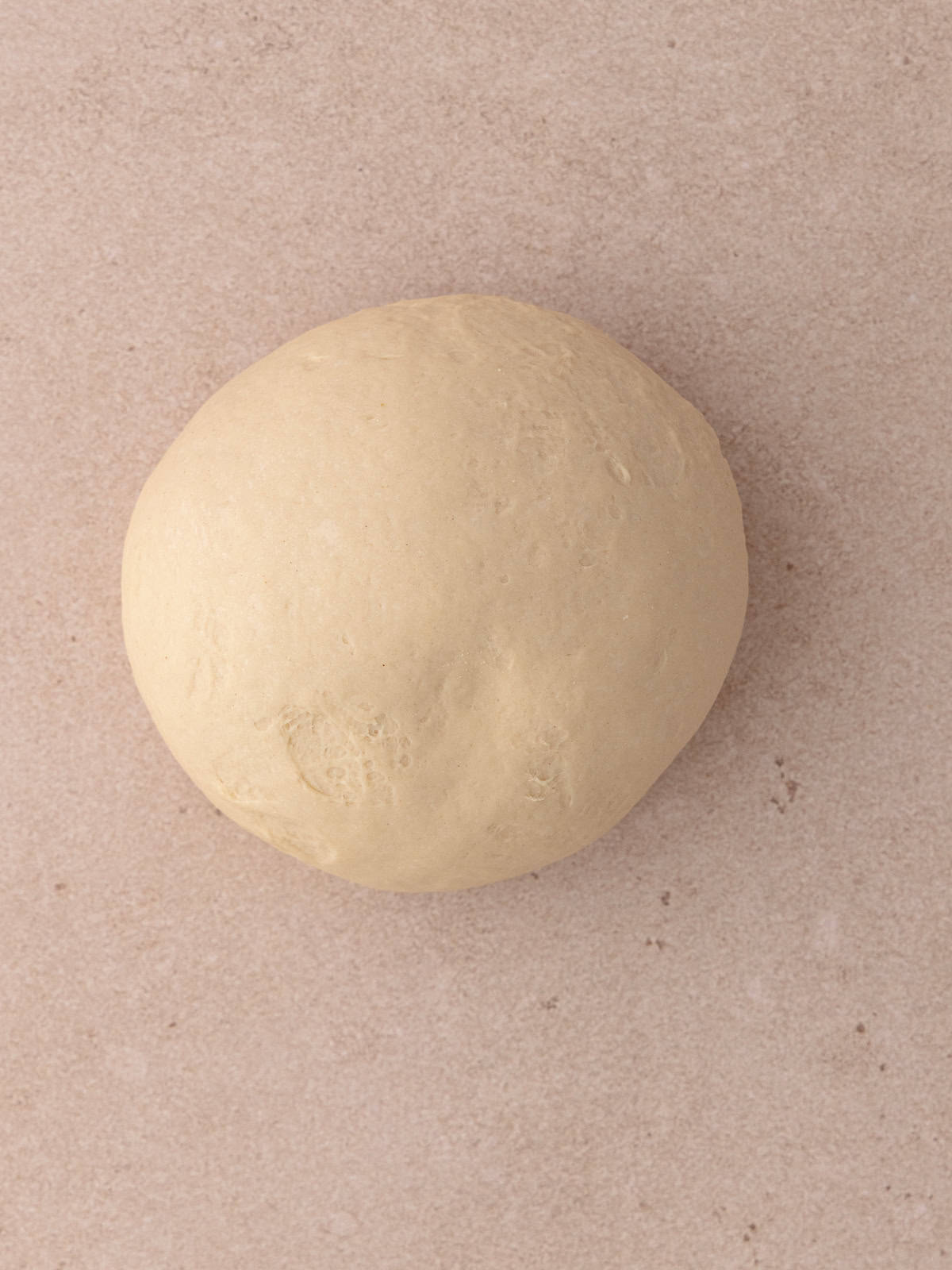 The kneaded dough has a slight indentation on it and is ready to double in size.