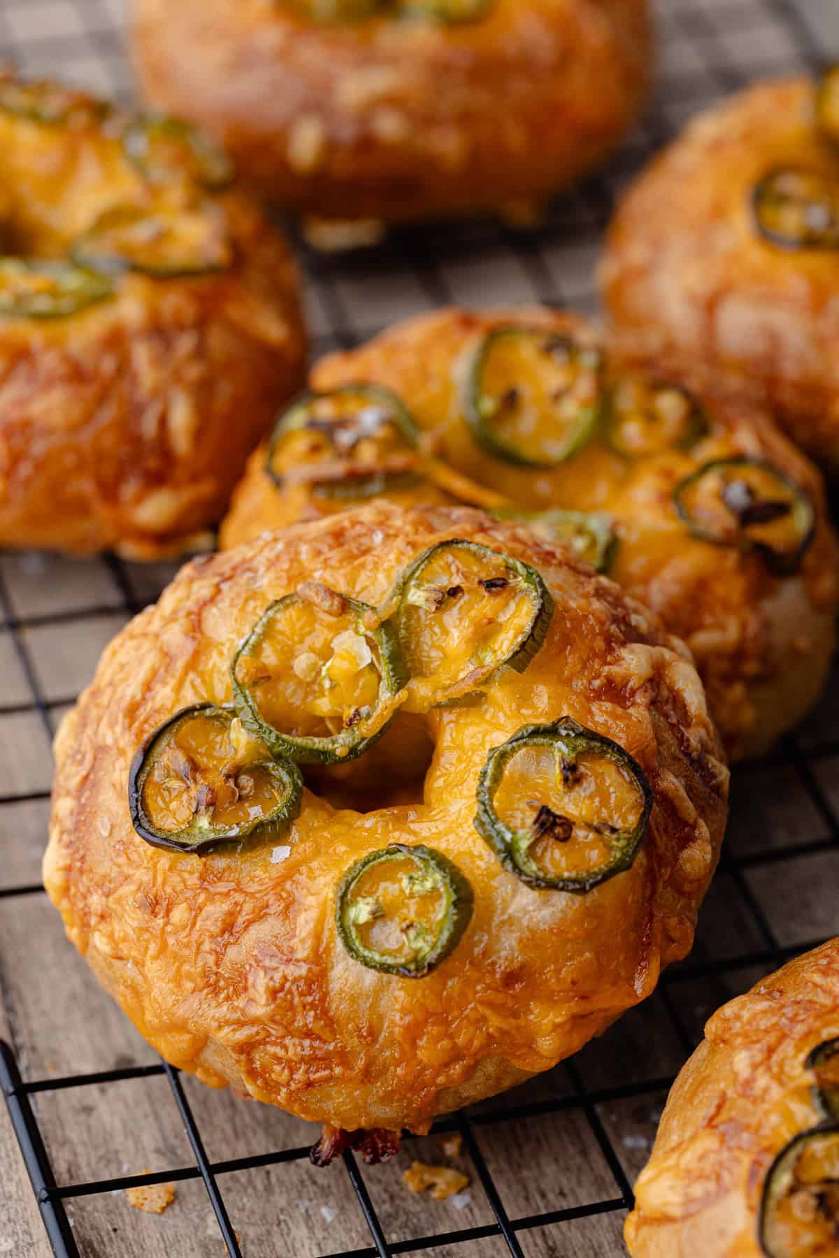 Jalapeño cheddar bagels sitting on a wire rack.