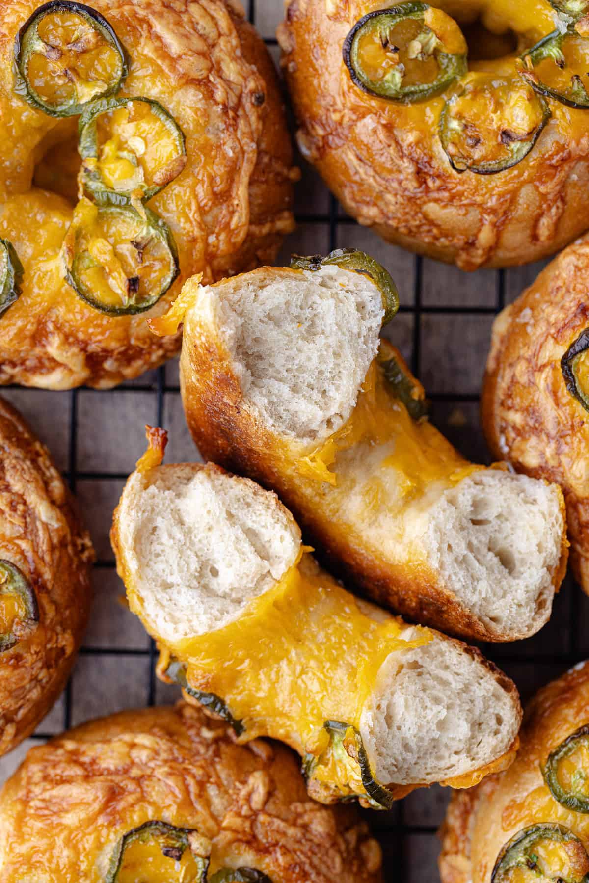 Jalapeño cheddar bagels on a wire cooling rack.