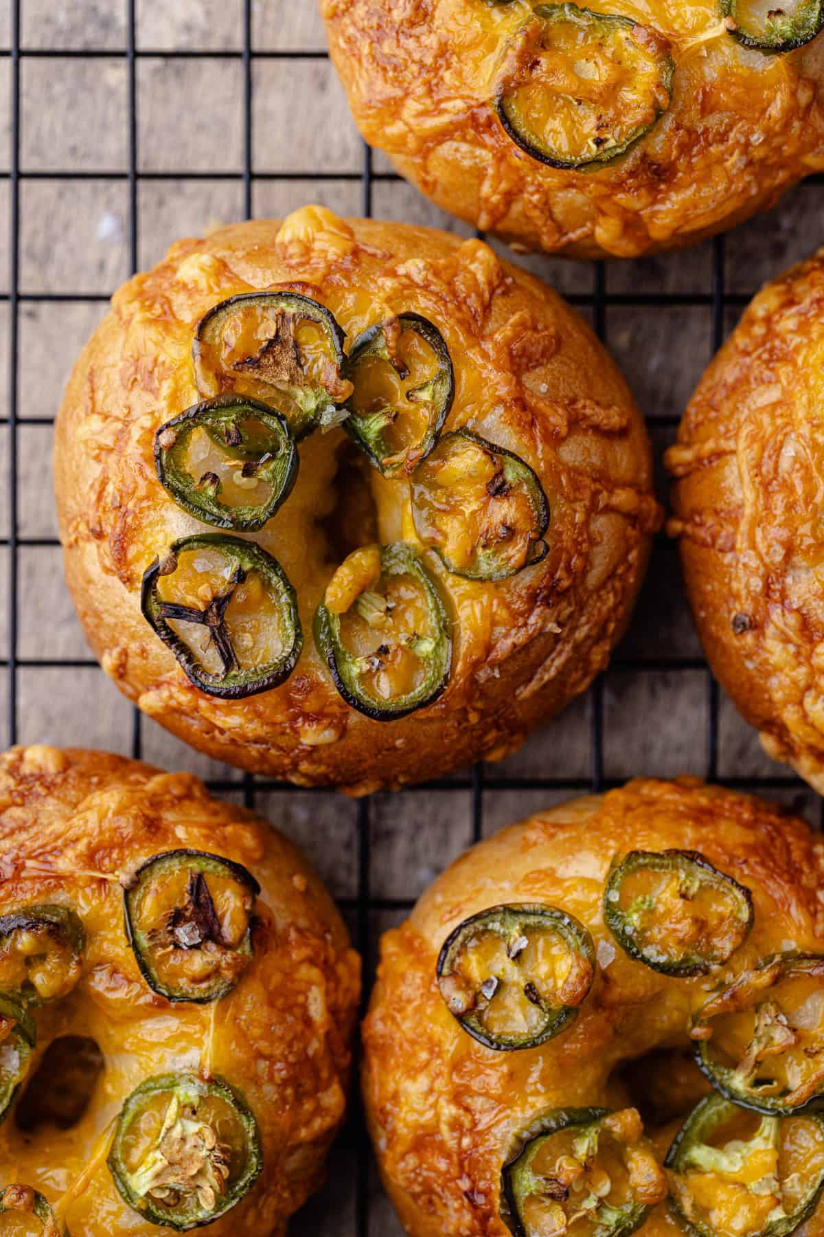 Jalapeño cheddar bagels sitting on a wire rack.