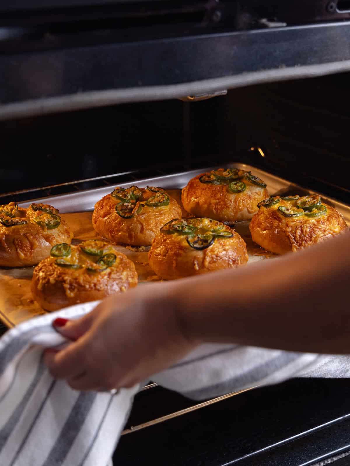 Baked jalapeno cheddar bagels are pulled out of the hot oven.