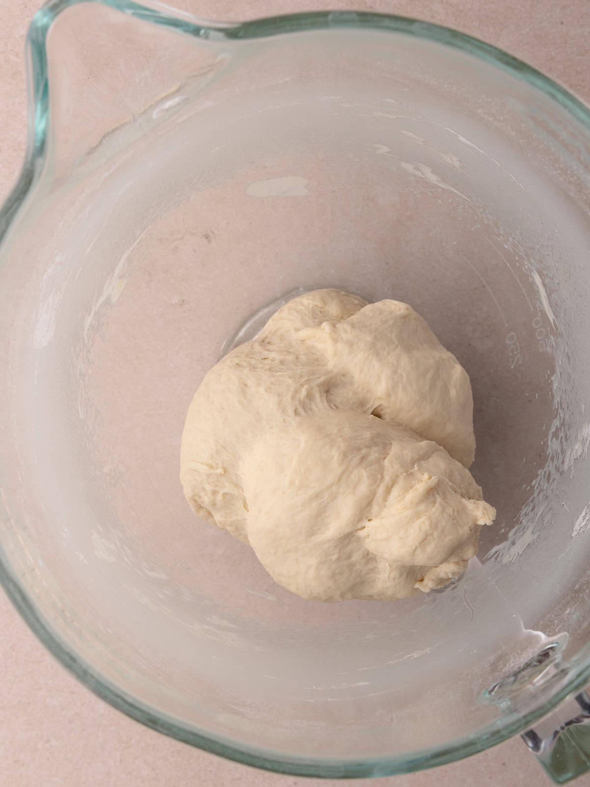 A ball of dough is sitting in a glass mixing bowl.