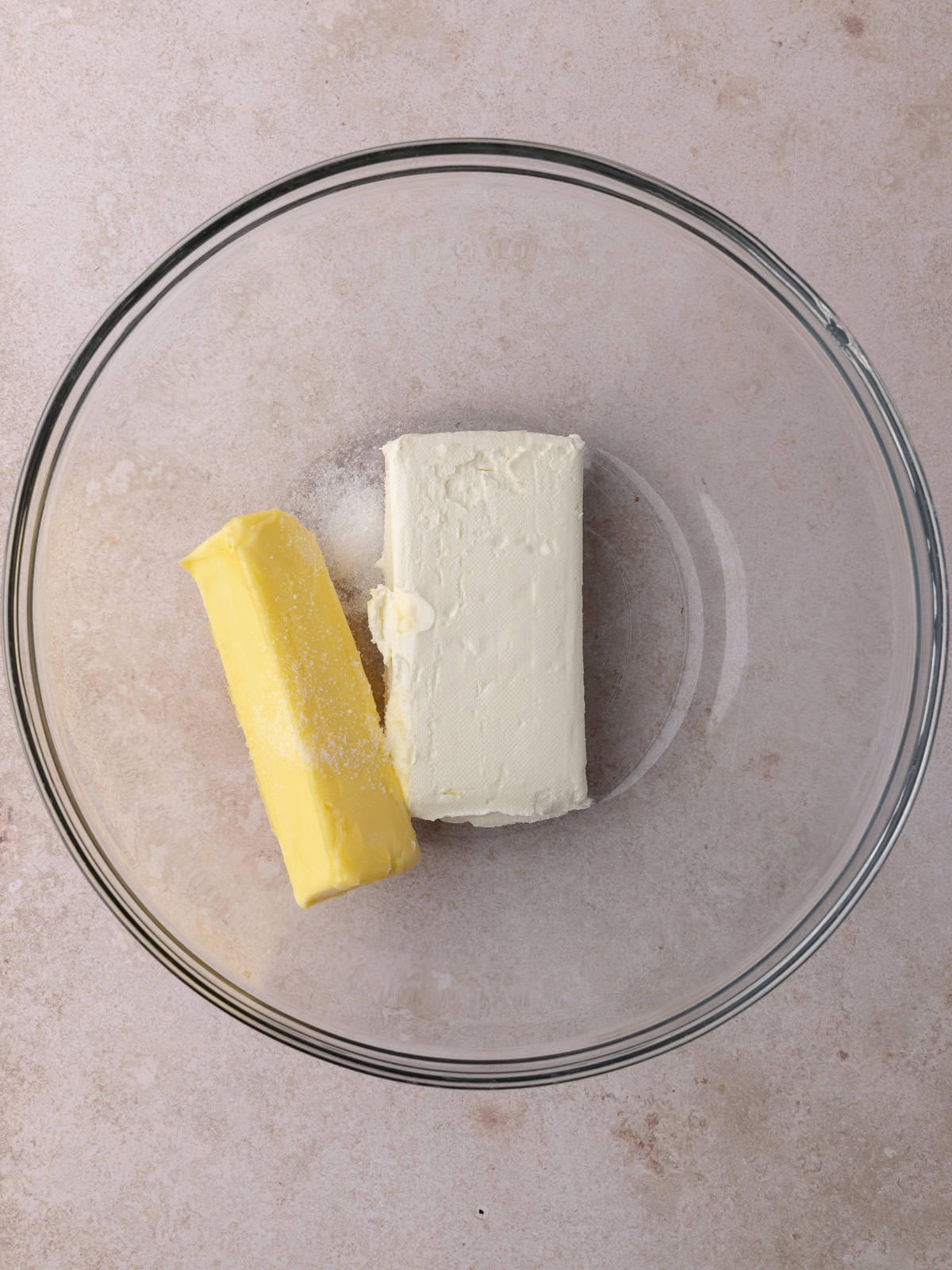 Softened butter, softened cream cheese and salt are in a large glass mixing bowl.