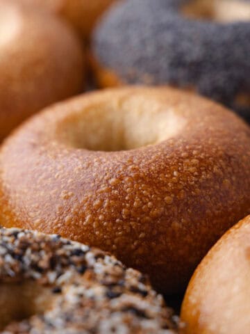 Overnight plain bagel with blistered crust sitting on a baking sheet, featured photo.