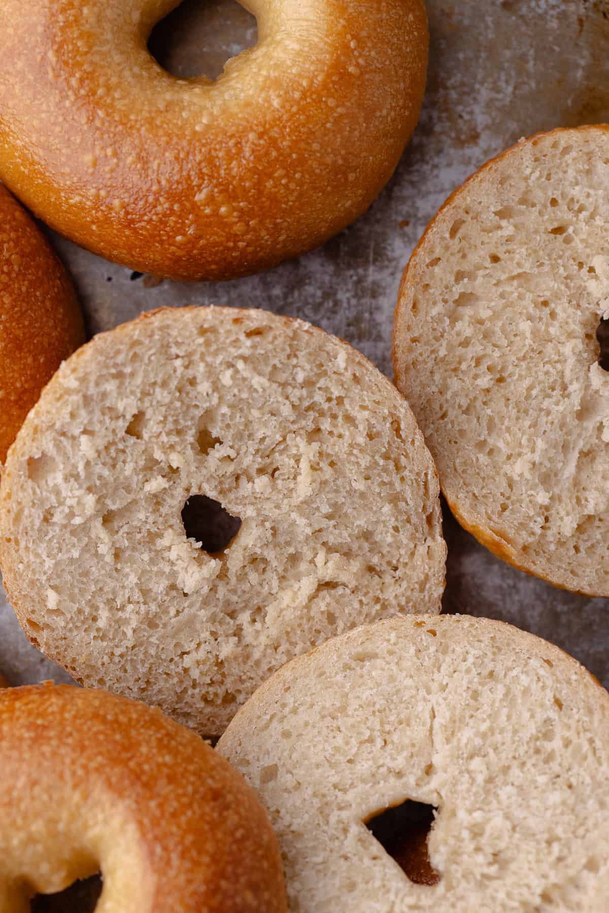 Overnight bagels are sliced down the middle and exposed to show the fluffy interior.