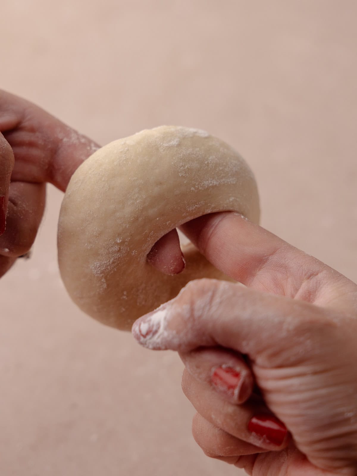 A finger creates a whole in the center of the dough ball and is twirled around the fingers.