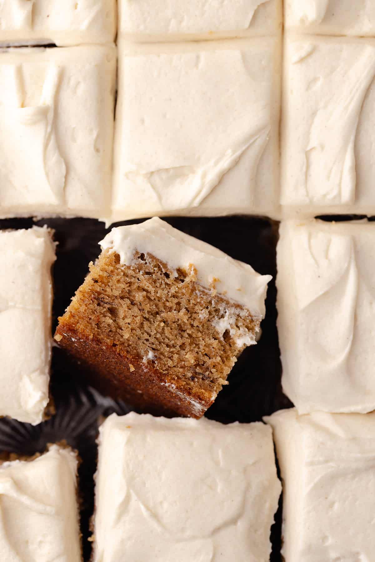 Maple cream cheese frosting is frosted on top of a spiced banana cake.