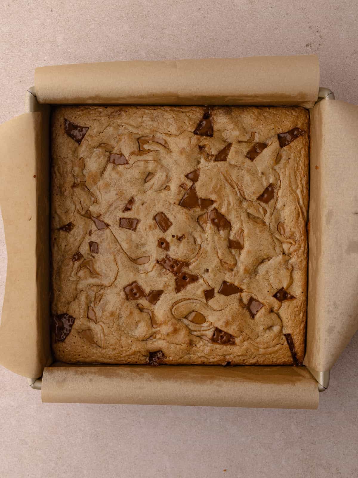 Toffee cookie butter blondie batter has been transferred to a baking pan lined with parchment paper.