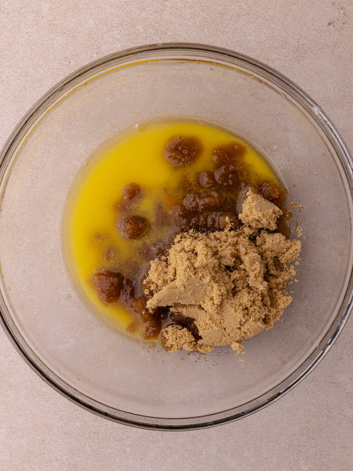 Melted butter and brown sugar are in a large glass mixing bowl.