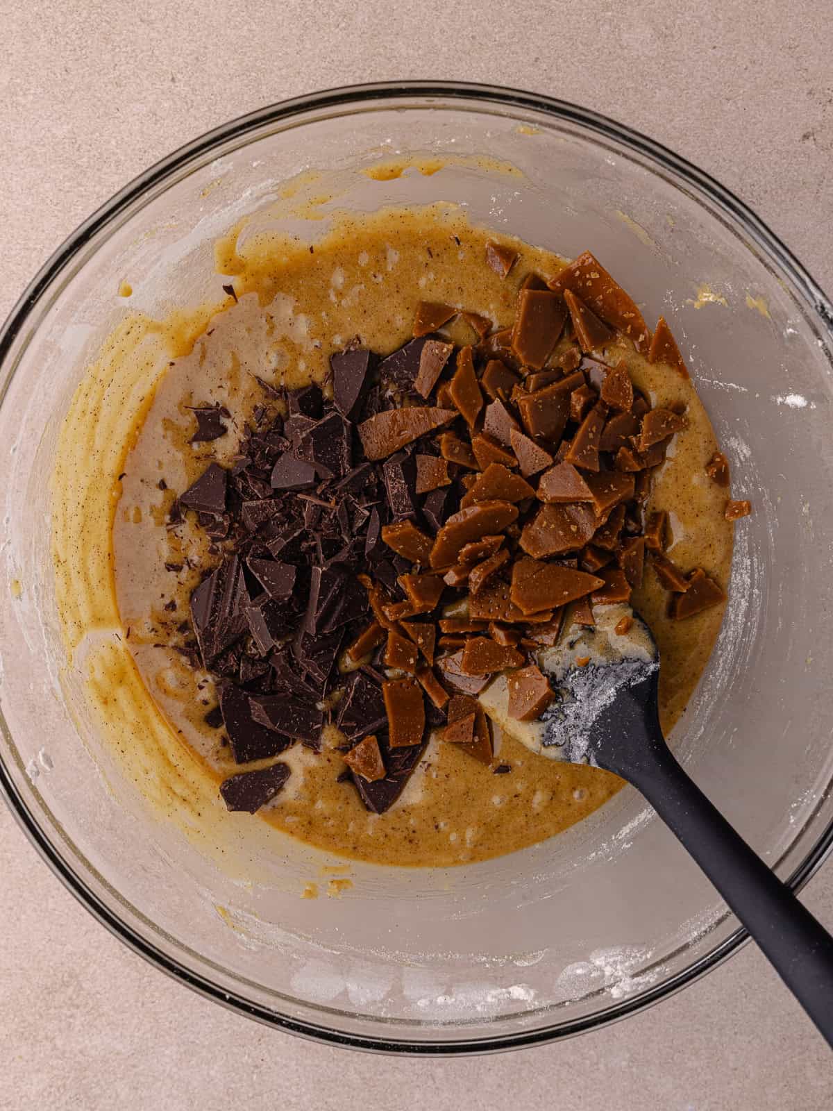 Chopped chocolate and toffee bits are added to the blondie batter that is in a large mixing bowl.