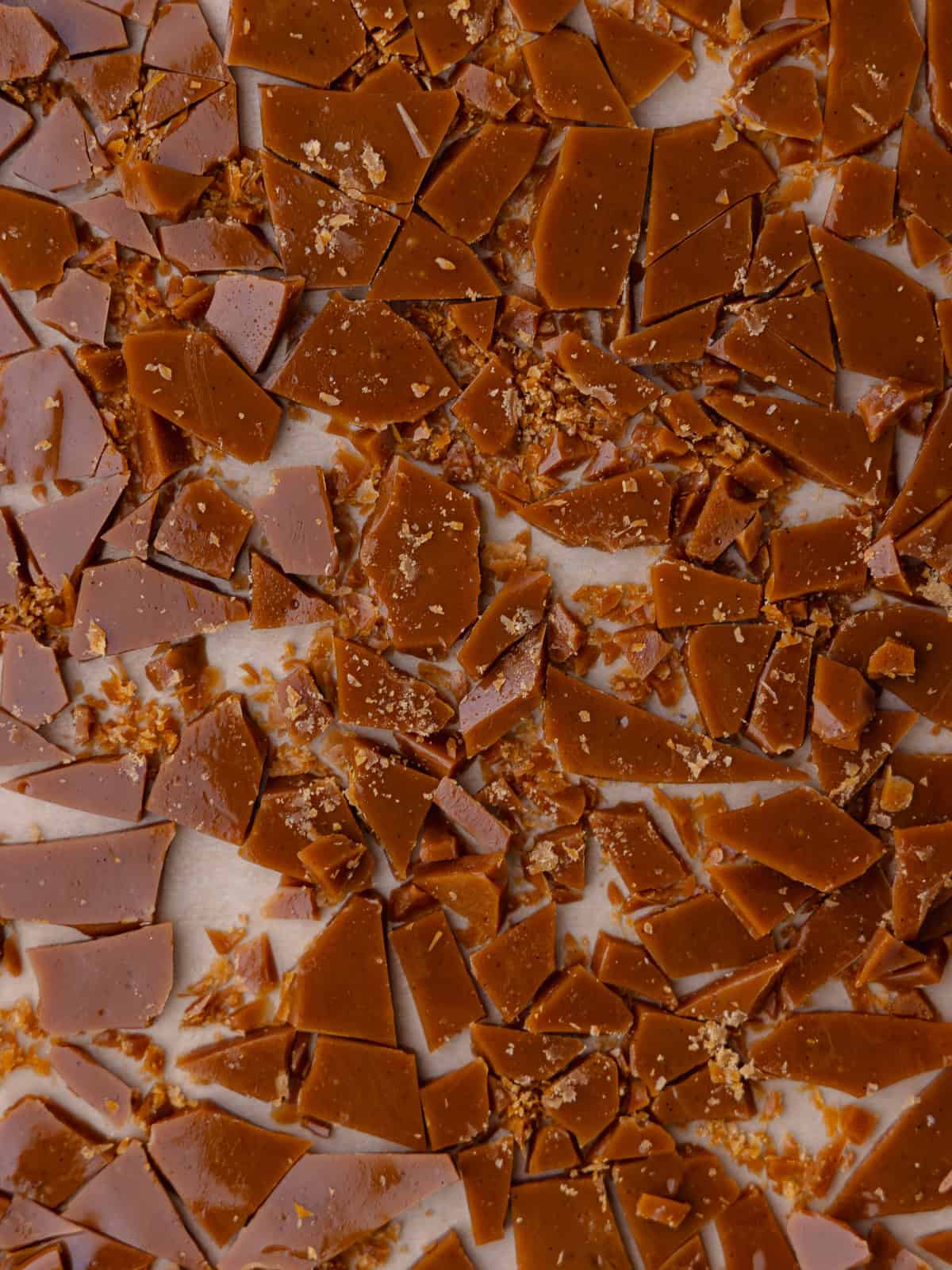 Crack toffee bits are sitting in a small baking tray lined with parchment paper.