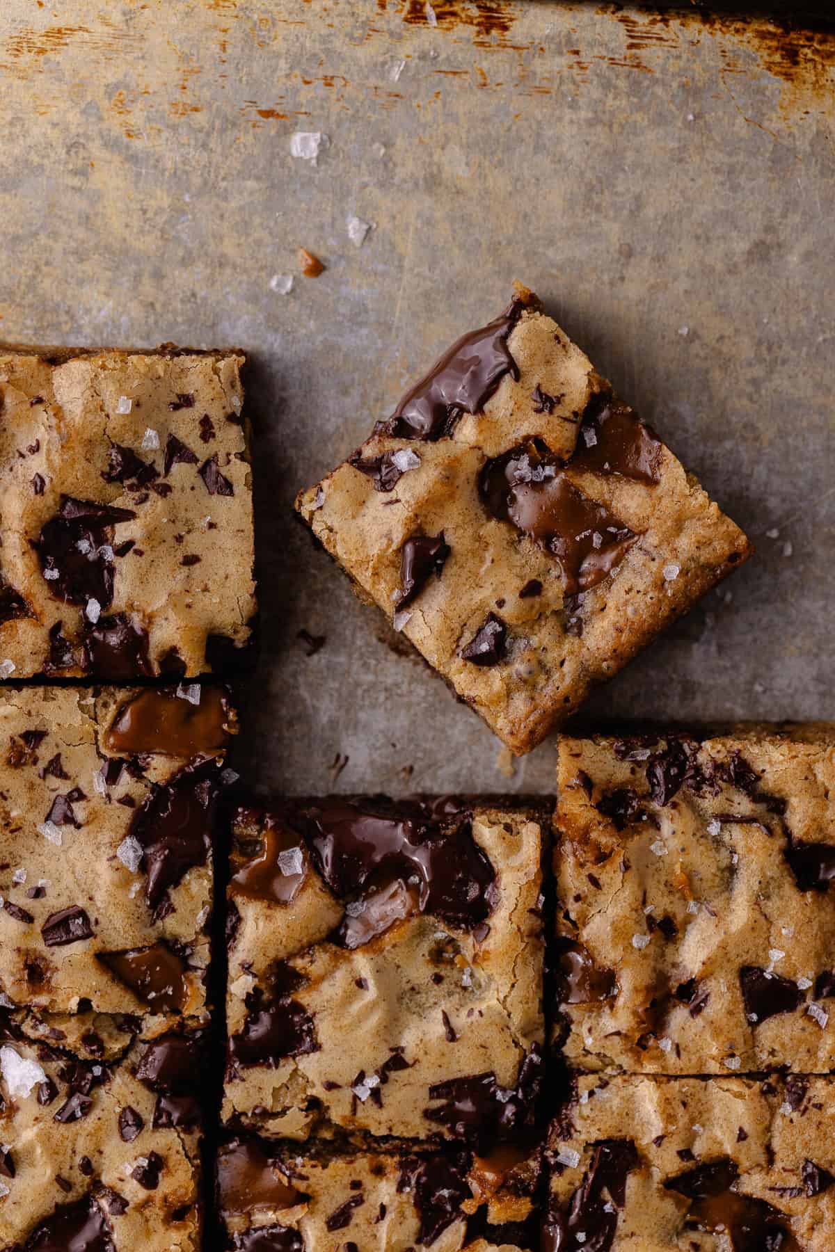 A close up of toffee espresso blondies cut in squares are sitting on a baking sheet.